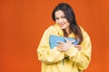 Beautiful young woman wearing casual standing isolated over orange background, reading a book Royalty Free Stock Photo