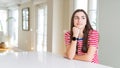 Beautiful young woman wearing casual stripes t-shirt with hand on chin thinking about question, pensive expression Royalty Free Stock Photo