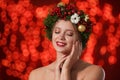 Beautiful young woman wearing Christmas wreath on blurred background. Royalty Free Stock Photo