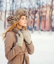Beautiful young woman wearing a coat and hat over snow in winter day Royalty Free Stock Photo