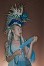 Beautiful young woman wearing costume with feather headgear over colored background