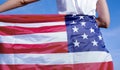 Beautiful young woman wearing denim shirt holding American flag in the open desert. Royalty Free Stock Photo