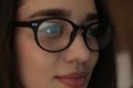 Beautiful young woman wearing glasses on blurred background, closeup.