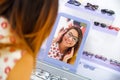 Beautiful young woman wearing glasses in optical store and looking in the mirror how she looks, in a blurred background Royalty Free Stock Photo