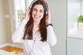 Beautiful young woman wearing headphones listening to music, enjoying and dancing happy Royalty Free Stock Photo