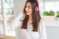 Beautiful young woman wearing headphones listening to music, enjoying and dancing happy Royalty Free Stock Photo