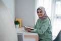 Beautiful young woman wearing a hijab smiling holding the holy book of the Koran Royalty Free Stock Photo