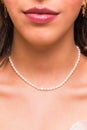 Beautiful young woman wearing a pearl necklace and golden earings. Beautiful valentine`s gift