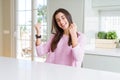 Beautiful young woman wearing pink sweater very happy and excited doing winner gesture with arms raised, smiling and screaming for