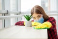 Beautiful young woman wearing protective gloves cleaning the desk in office Royalty Free Stock Photo