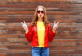 Beautiful young woman wearing a red leather jacket in autumn over wooden