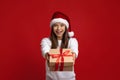 Beautiful Young Woman Wearing Santa Hat Giving Christmas Present At Camera Royalty Free Stock Photo