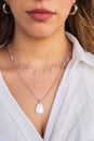 Young woman wearing silver clear and pearl necklaces and silver earrings