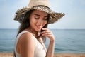 Beautiful young woman wearing straw hat on beach. Stylish headdress Royalty Free Stock Photo