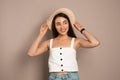 Beautiful young woman wearing straw hat on beige background. Stylish headdress Royalty Free Stock Photo