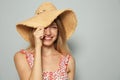Beautiful young woman wearing straw hat on light grey background, space for text. Stylish headdress Royalty Free Stock Photo