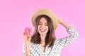 Beautiful young woman wearing stylish hat with donut on light pink background Royalty Free Stock Photo