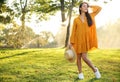 Beautiful young woman wearing stylish yellow dress with straw hat in park Royalty Free Stock Photo