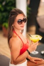 Beautiful young woman wearing swimsuit drinking a colorful cocktail sitting on a cabin of the beach club bar. Stunning Royalty Free Stock Photo