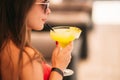 Beautiful young woman wearing swimsuit drinking a colorful cocktail sitting on a cabin of the beach club bar. Stunning Royalty Free Stock Photo