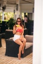 Beautiful young woman wearing swimsuit drinking a colorful cocktail sitting on a cabin of the beach club bar. Stunning Royalty Free Stock Photo