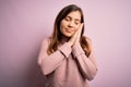 Beautiful young woman wearing turtleneck sweater over pink isolated background sleeping tired dreaming and posing with hands Royalty Free Stock Photo