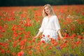 beautiful young woman wearing white dress walking thru a blooming summer field Royalty Free Stock Photo