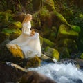 Beautiful young woman in a white dress in the middle of a forest