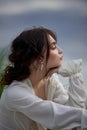 Beautiful young woman in white dress resting on shore lake pond river. Professional makeup and hairstyle with curled hair Royalty Free Stock Photo