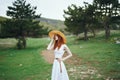 Beautiful young woman in a white dress is standing on a meadow in the mountains Royalty Free Stock Photo