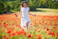 Beautiful young woman in white dress walking in poppy field on a summer day Royalty Free Stock Photo