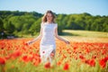 Beautiful young woman in white dress walking in poppy field on a summer day Royalty Free Stock Photo