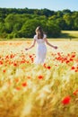 Beautiful young woman in white dress walking in poppy field on a summer day Royalty Free Stock Photo