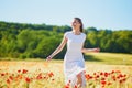 Beautiful young woman in white dress walking in poppy field on a summer day Royalty Free Stock Photo