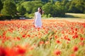 Beautiful young woman in white dress walking in poppy field on a summer day Royalty Free Stock Photo