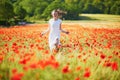 Beautiful young woman in white dress walking in poppy field on a summer day Royalty Free Stock Photo