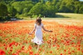 Beautiful young woman in white dress walking in poppy field on a summer day Royalty Free Stock Photo