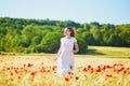 Beautiful young woman in white dress walking in poppy field on a summer day Royalty Free Stock Photo