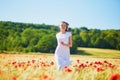 Beautiful young woman in white dress walking in poppy field on a summer day Royalty Free Stock Photo