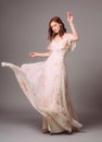 Beautiful young woman in white evening dress with floral print. Studio portrait of ginger girl in evening gown Royalty Free Stock Photo