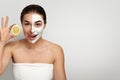 Beautiful young woman with white mask of clay on face clean fresh skin holding slices of fresh lemon . Girl beauty face Royalty Free Stock Photo