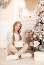 Beautiful young woman in white near the Christmas tree. Beautiful girl celebrates Christmas