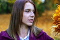 Beautiful young woman in a white shirt and purple coat looks at a bouquet of dry yellow leaves. Royalty Free Stock Photo