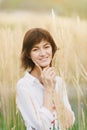 Beautiful young woman in a white shirt smiling standing against a background of tall yellow grass Royalty Free Stock Photo