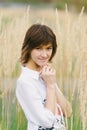 Beautiful young woman in a white shirt smiling  standing against a background of tall yellow grass Royalty Free Stock Photo