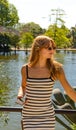 Beautiful young woman in a white tight dress with black stripes and long hair standing leaning against a fence looking to her left Royalty Free Stock Photo