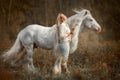 Beautiful young woman with white tinker cob in an autumn