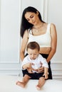 A beautiful young woman in a white top and black leggings holds her little son in a white shirt and black shorts. Family look Royalty Free Stock Photo
