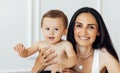 A beautiful young woman in a white top and black leggings holds her little son in a black short Royalty Free Stock Photo