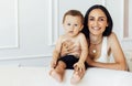 A beautiful young woman in a white top and black leggings holds her little son in a black short Royalty Free Stock Photo